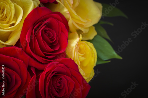 Part of a bouquet of red and yellow roses in a basket close-up.