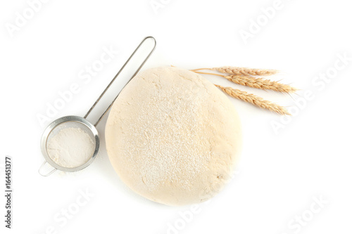 Fresh raw dough, sieve and wheat on white background