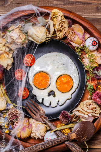 Fried eggs in the shape of a skull and fresh tomatoes.