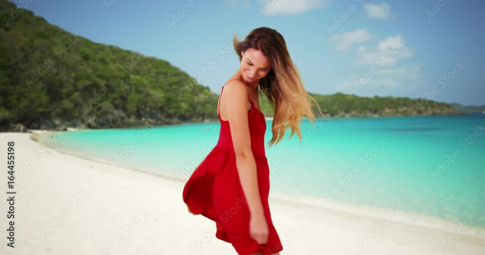 Beautiful millennial girl in red sundress dancing on the beach on sunny day. Happy young Caucasian woman enjoying vacation on tropical island by the water. 4k