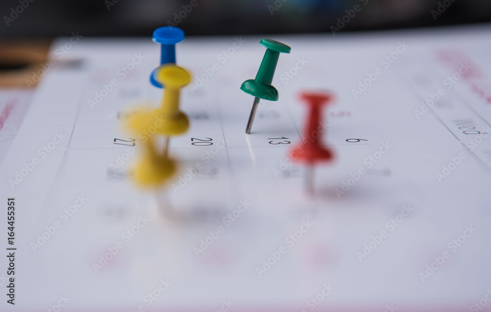 closeup colorful pins push marking on a calendar. busy schedule . closeup colorful pins push marking on a calendar. busy schedule .