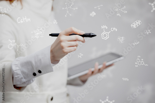 Woman chemist working with chemical formulas on grey background.