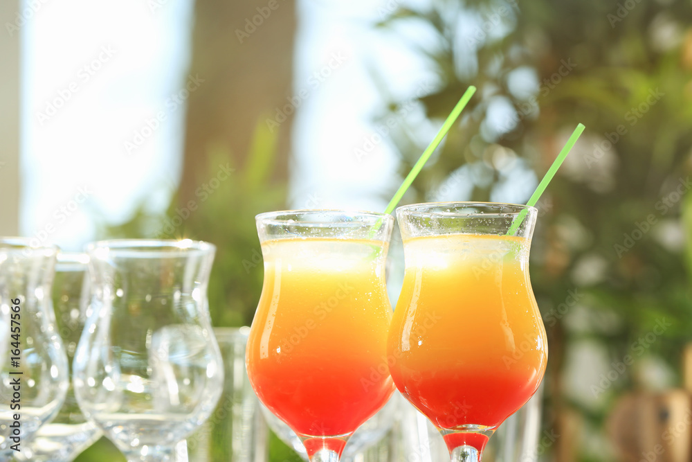 Glasses of delicious tequila sunrise cocktails on blurred background