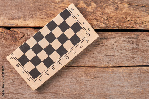 Folded checker board, top view. Closed box with checkers on old wooden background. photo