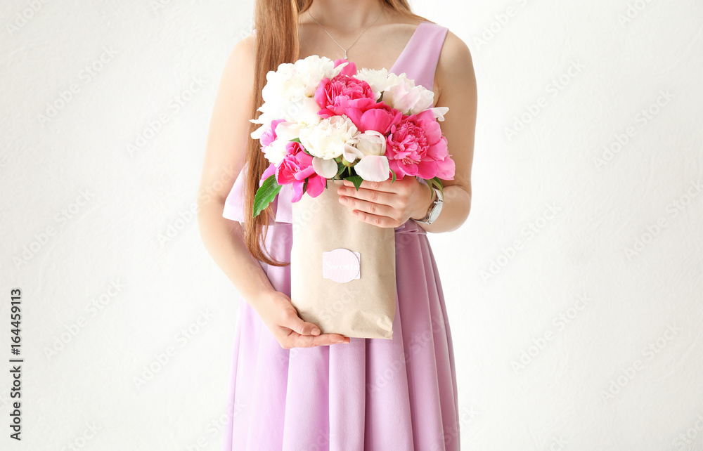 Young woman holding beautiful peonies on white background