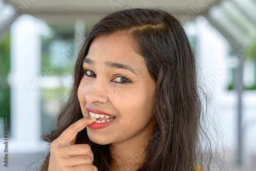 Thoughtful young Indian woman biting her finger