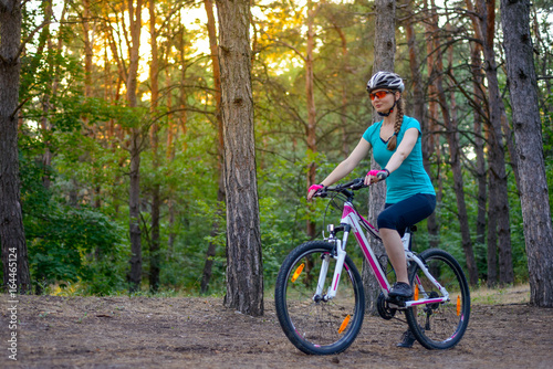 Young Woman Riding the Bike on the Trail in Beautiful Fairy Pine Forest. Adventure and Travel Concept. © Maksym Protsenko