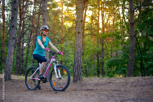 Young Woman Riding the Bike on the Trail in Beautiful Fairy Pine Forest. Adventure and Travel Concept.