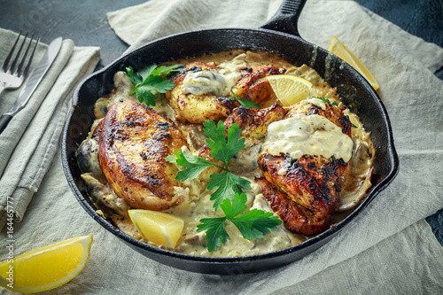 Creamy chicken fellets supremes in mushroom sauce with parsley In rustic cast iron skillet.