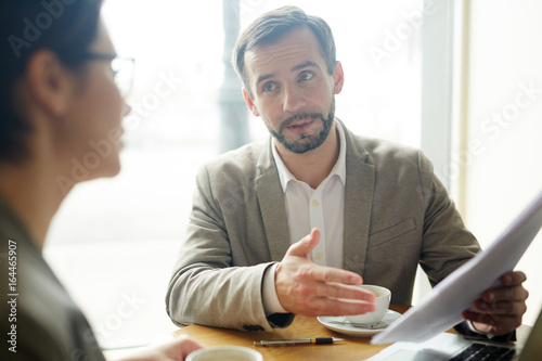 Confident agent explaining main points of financial contract to client photo