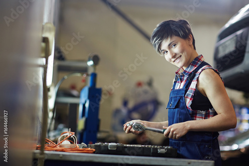 Young happy technician with hand-tool looking at camera