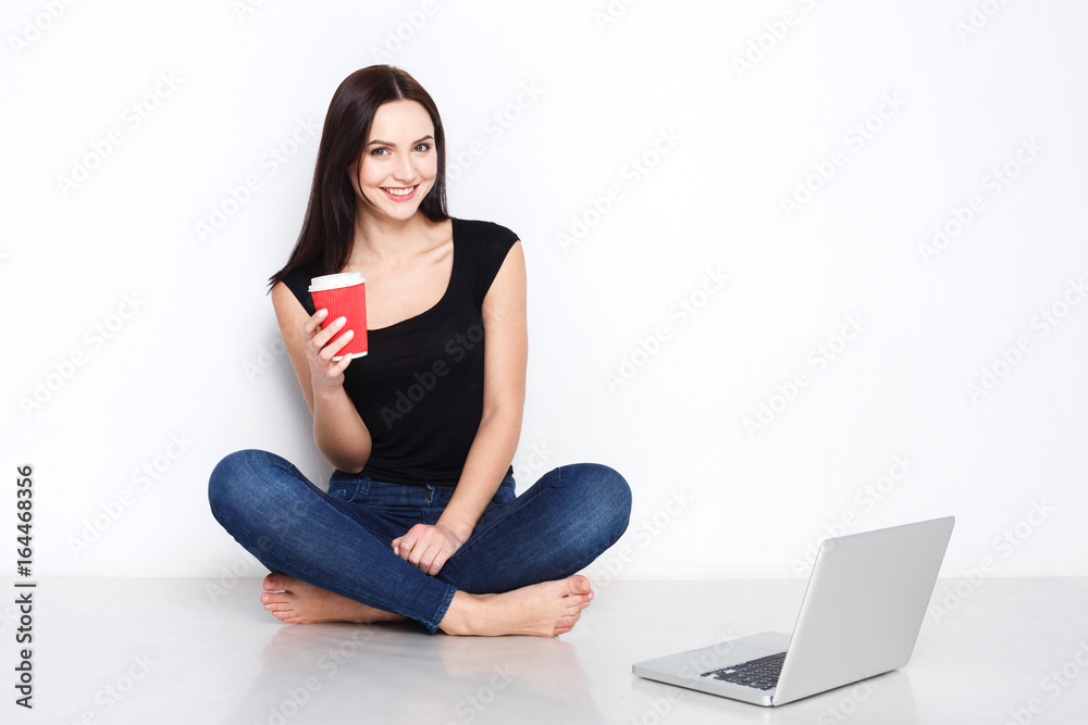 Fototapeta premium Woman using laptop sitting on the studio floor