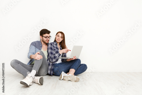 Casual couple shopping online with laptop, studio shot