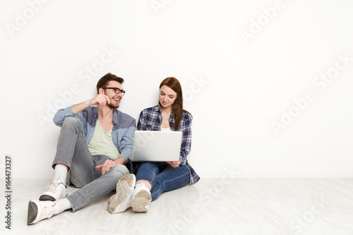 Smiling couple web-surfing on laptop, studio shot
