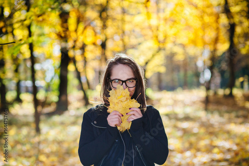 Beautyful woman in glasses throwing yellow leaves in the air
