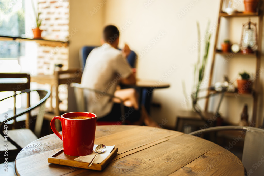Red cup of coffee in a cafe on table. Place for rest - obrazy, fototapety, plakaty 