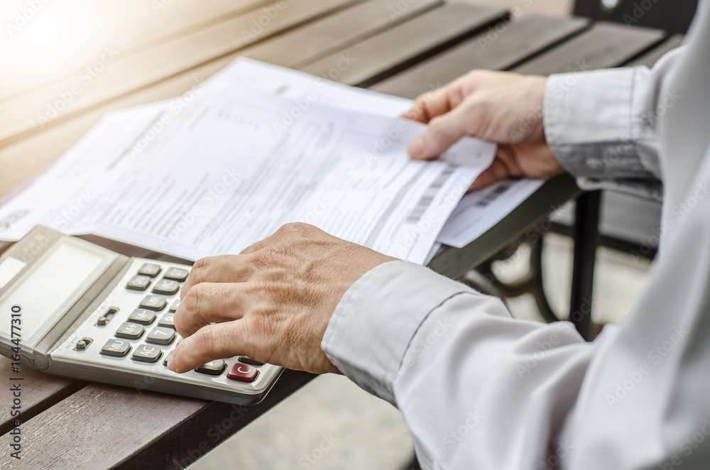 Man using calculator and thinking about cost with paying bills Man using calculator and thinking about cost with paying bills