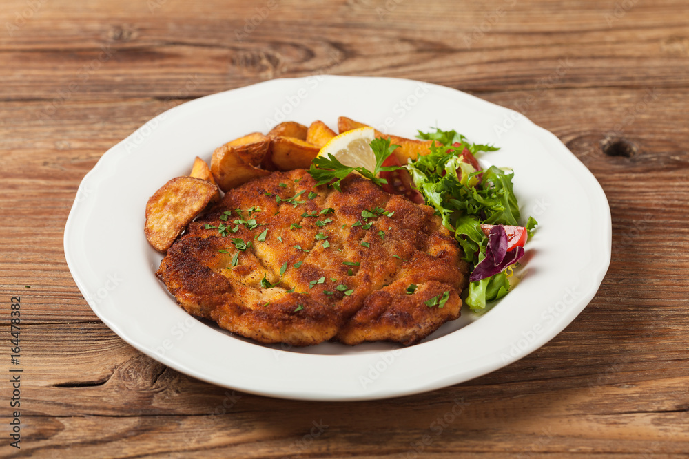 Chicken schnitzel, served with roasted potatoes and salad.