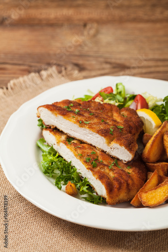 Chicken schnitzel, served with roasted potatoes and salad.