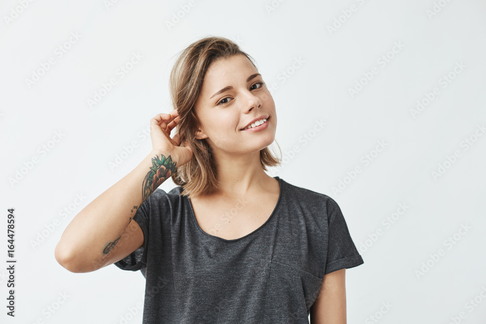 Cute young beautiful girl smiling looking at camera correcting hair over white background. Cute young beautiful girl smiling looking at camera correcting hair over white background.