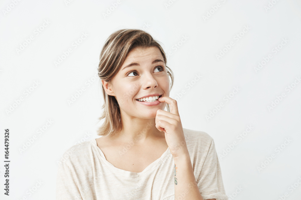 Beautiful young happy girl smiling biting nail over white background. Beautiful young happy girl smiling biting nail over white background.
