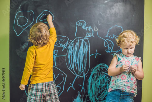 Boy and girl paint with chalk on a blackboard photo