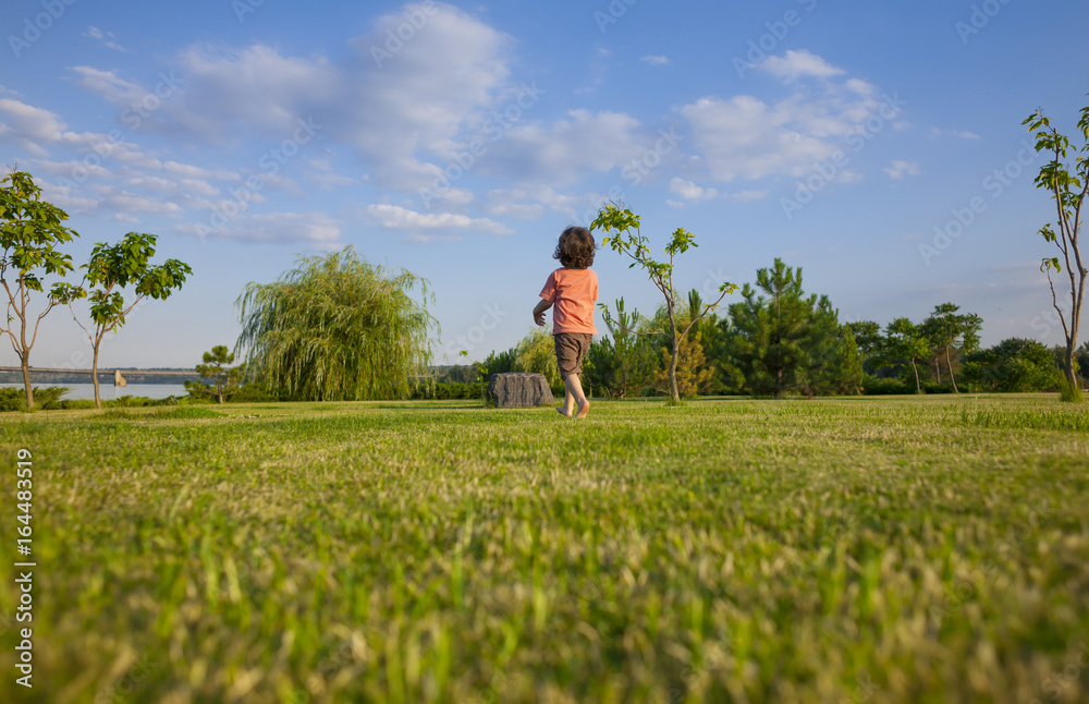 The boy runs along the grass.