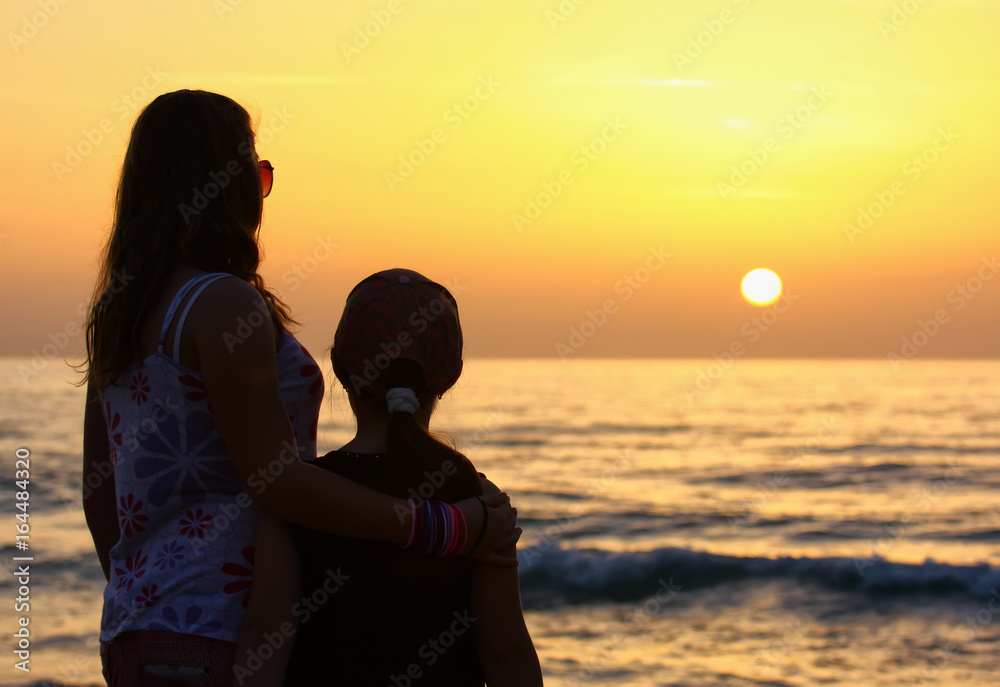 Two girlfriends in the evening on the shore of the Mediterranean Sea
