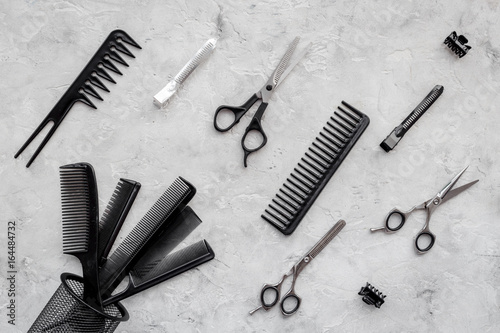 Combs and hairdresser tools on grey table background top view
