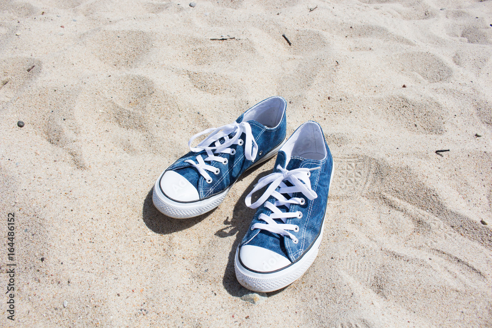 Naklejka premium blue sneakers on white sand