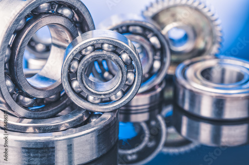 Group of various ball bearings close up on nice blue background with reflections photo