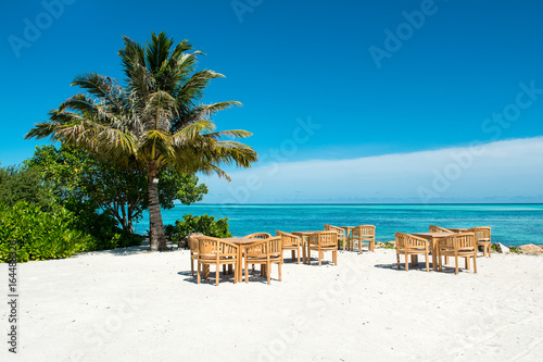 Wooden tables and chairs of tropical restaurant on the sand