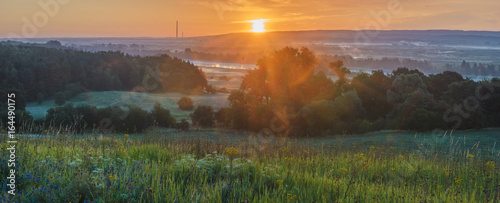 Foggy summer morning over the valley, fog and rising sun