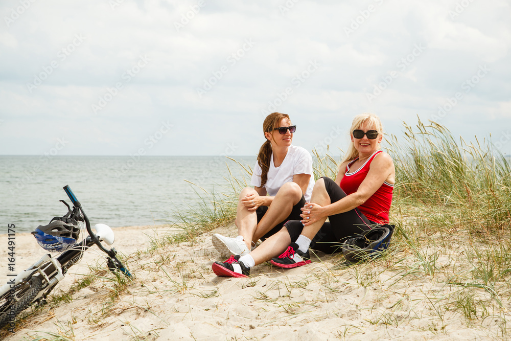 Fototapeta premium Women resting after riding bike on the beach 