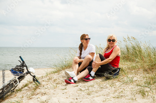 Women resting after riding bike on the beach 