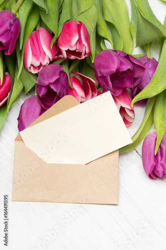 Tulip bouquet and envelope on white wooden background, copy space