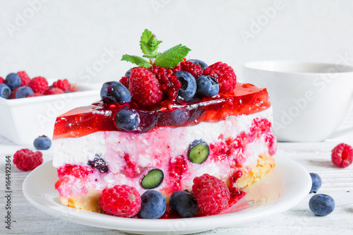 Delicious cheesecake with raspberries, blueberries and mint and cup of coffee