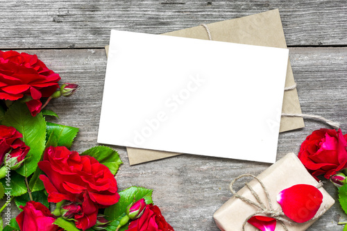 Bouquet of red roses with a blank greeting card and envelope with gift box