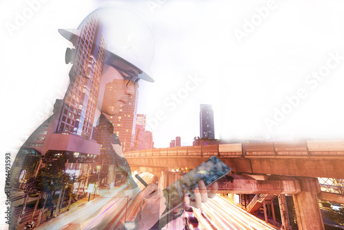 Double exposure of Engineer or Architecture man in working shirt and safety helmet working with tablet in night building background , business and construction concept