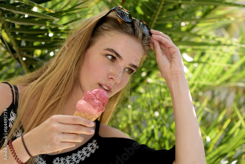 Junge Frau mit Eistüte vor tropischer Vegetation
