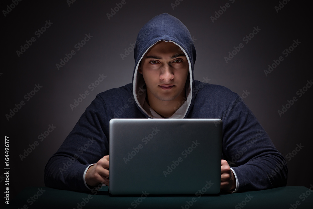Young man wearing a hoodie sitting in front of a laptop computer Young man wearing a hoodie sitting in front of a laptop computer