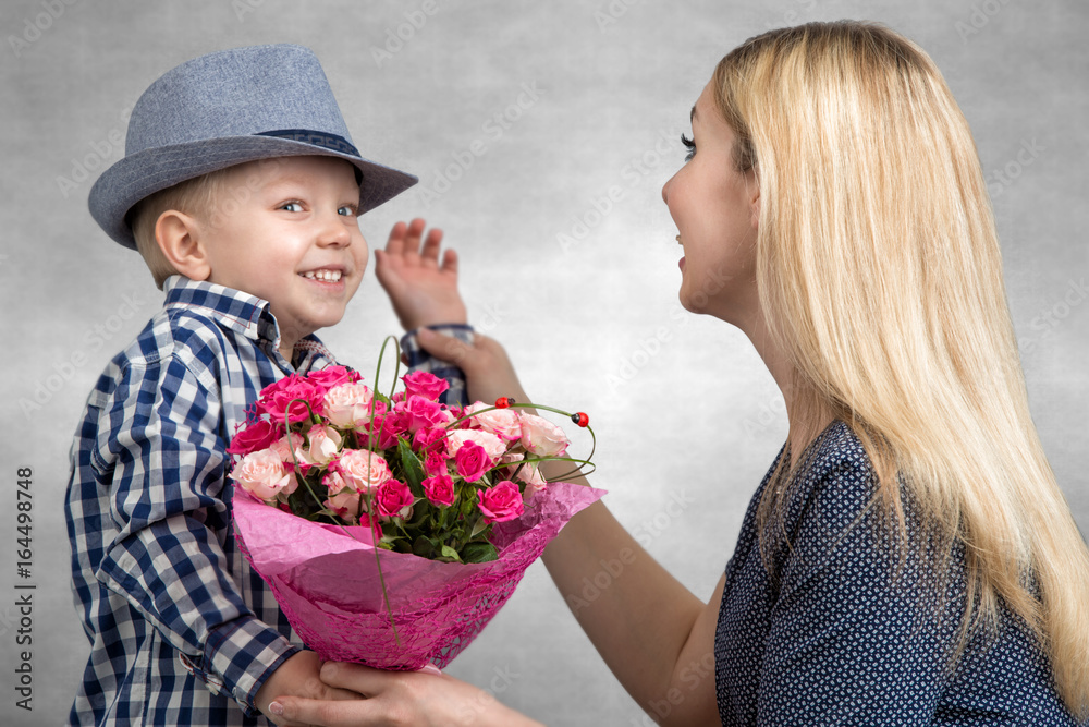 Small son gives his beloved mother a beautiful bouquet of pink roses . Spring, concept of family vacation. Women's day,mother's day. Small son gives his beloved mother a beautiful bouquet of pink roses . Spring, concept of family vacation. Women's day,mother's day.