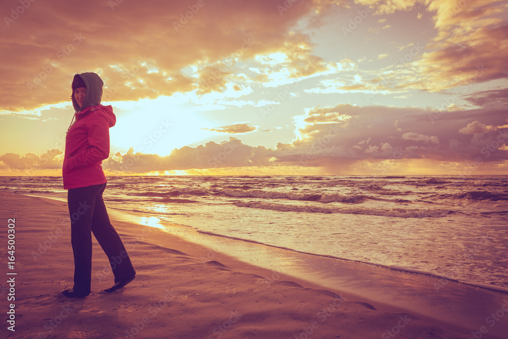 Woman enjoying dramatic sunset on sea