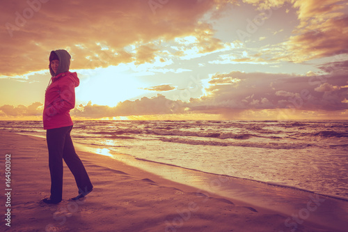 Woman enjoying dramatic sunset on sea