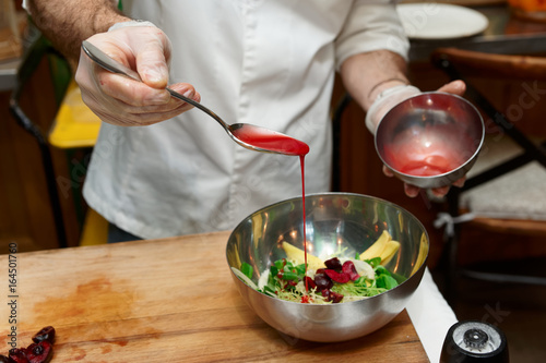 Chef is adding sauce to bowl with vegetable appetizer