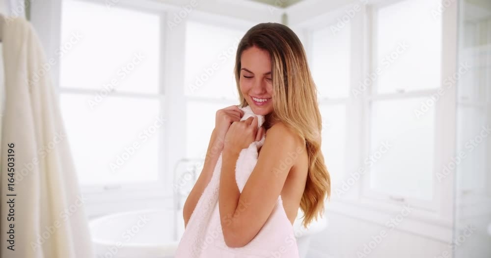 Young Caucasian woman looking at camera with flirty expression, holding towel over naked body in bathroom. Attractive female with clean, healthy skin smiling at camera playfully. 4k Young Caucasian woman looking at camera with flirty expression, holding towel over naked body in bathroom. Attractive female with clean, healthy skin smiling at camera playfully. 4k