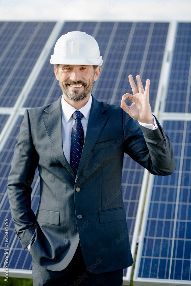 Solar panel energy choice of businessman. Man in business suit showing ok with his fingers. Solar panel energy choice of businessman. Man in business suit showing ok with his fingers.