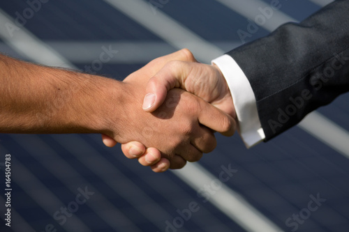 Agreeman handshake, solar panel on background. Foreman and businessman shaking hands.