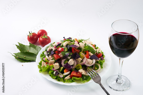 Fresh green organic salad with chicken meat and red dry wine isolated on white background with copy space.