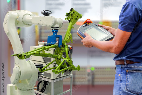 Engineer using wireless remote for control industrial robot	